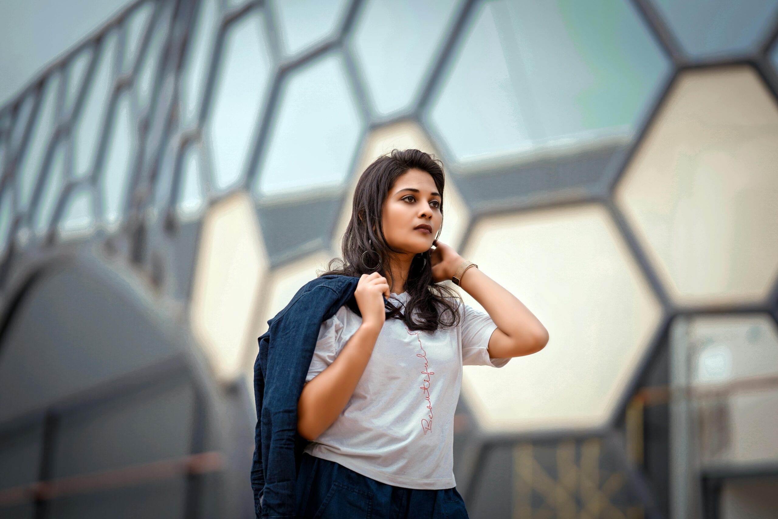 A woman in casual clothing walks by hexagonal patterned building facade.