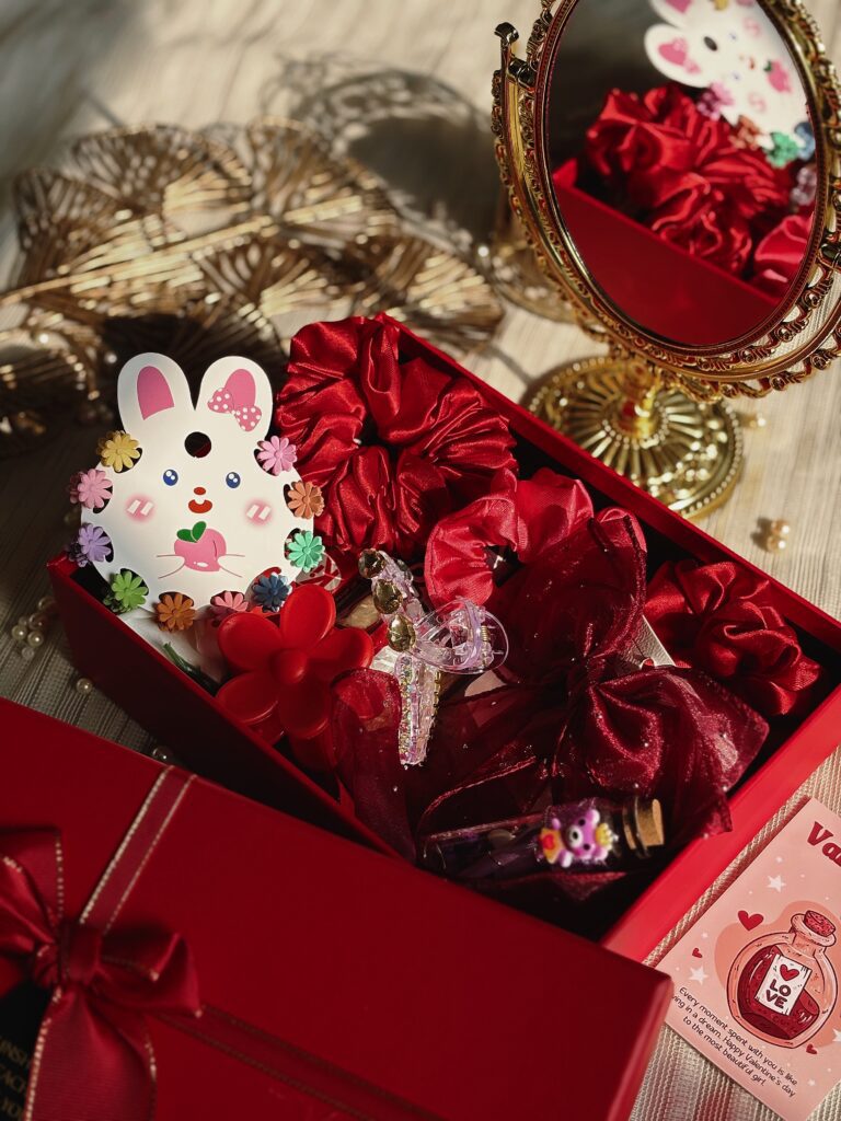 Cute accessories hamper with cute scrunchies and chocolates in a reddish hamper