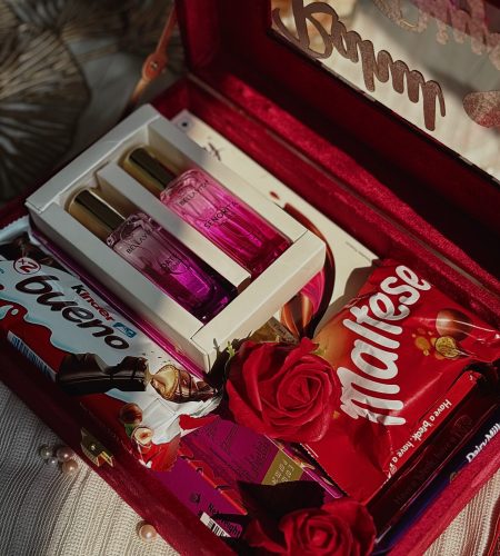Red gift box with chocolates, roses, and perfume arranged for a romantic celebration